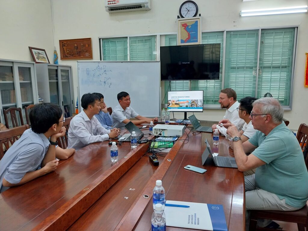 Vietnamesische und deutsche Wissenschaftler an einem großen Besprechungstisch aus braunem Holz