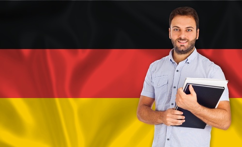 Deutsche Landesfahne im Hintergrund, davor ein Student mit Büchern und Heften im Arm